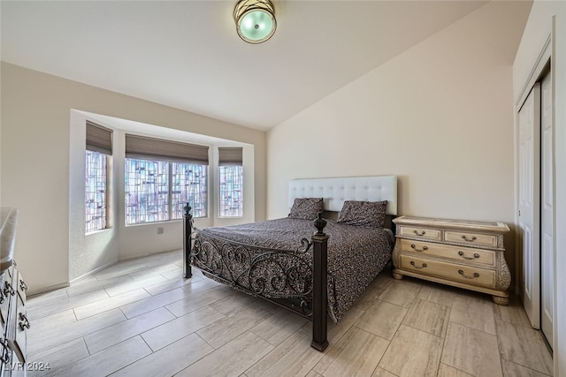 bedroom featuring a closet, light hardwood / wood-style floors, and vaulted ceiling