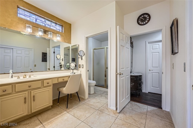 bathroom featuring toilet, vanity, tile patterned floors, and a shower with door