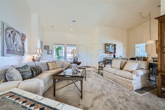 carpeted living room featuring high vaulted ceiling and a chandelier