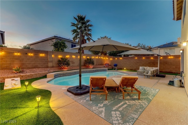 pool at dusk with a patio and an outdoor hangout area