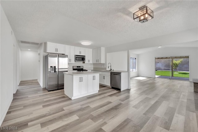 kitchen with sink, stainless steel appliances, a textured ceiling, and white cabinetry