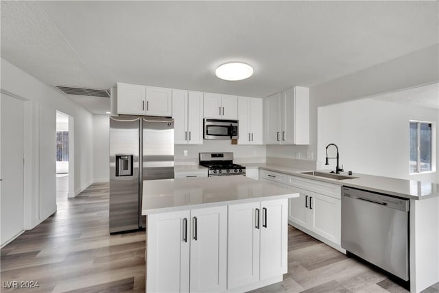 kitchen with sink, white cabinets, kitchen peninsula, and appliances with stainless steel finishes