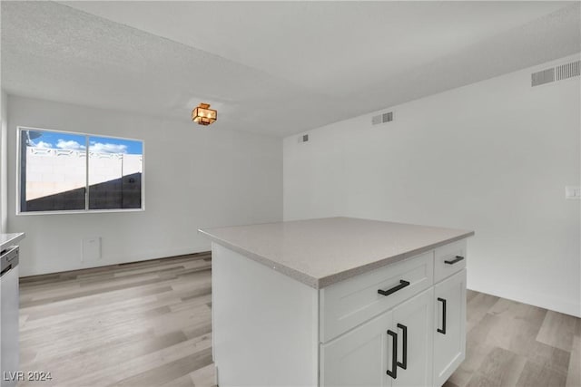 kitchen featuring light hardwood / wood-style flooring, white cabinetry, a center island, and dishwasher