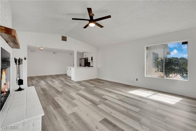 unfurnished living room featuring lofted ceiling, a textured ceiling, ceiling fan, and light hardwood / wood-style floors