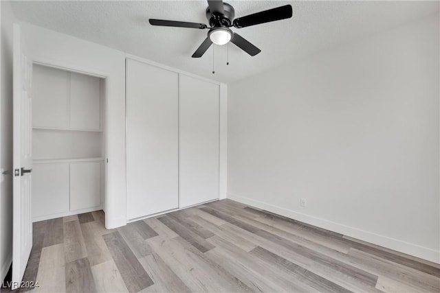 unfurnished bedroom with a textured ceiling, ceiling fan, light hardwood / wood-style floors, and a closet