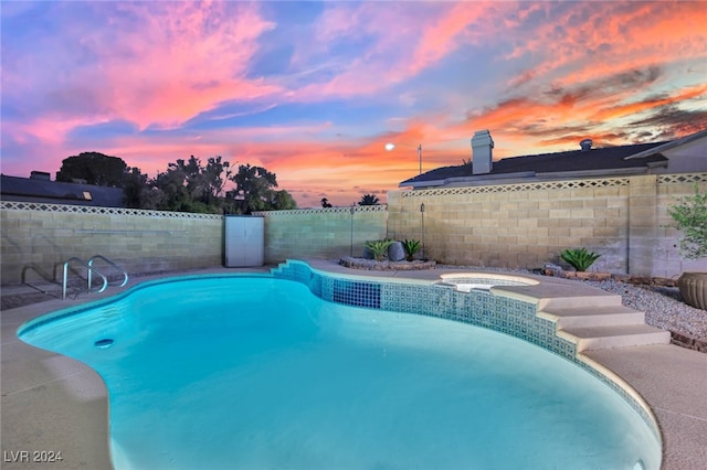 pool at dusk with an in ground hot tub