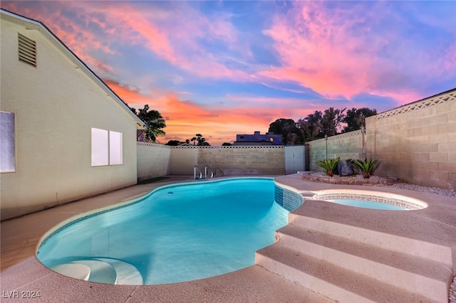 pool at dusk featuring an in ground hot tub