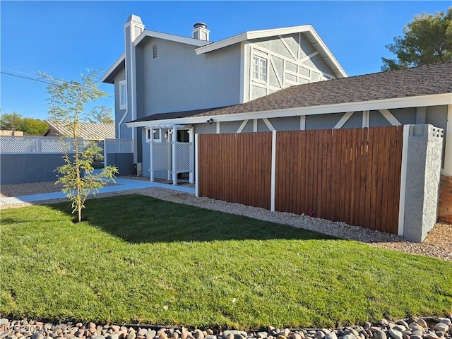back of property with a yard, stucco siding, and fence