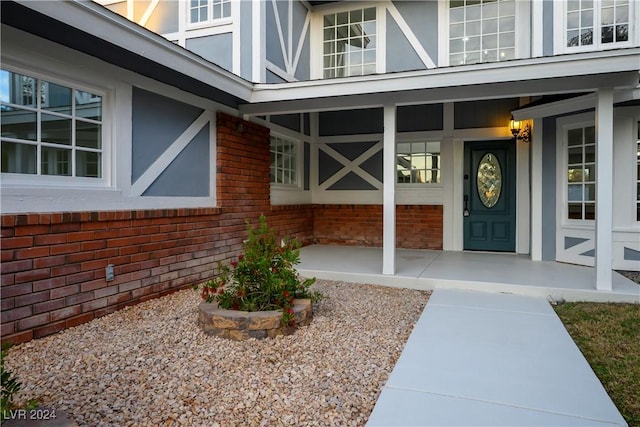property entrance with a porch, stucco siding, and brick siding