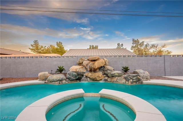 view of swimming pool with a pool with connected hot tub and a fenced backyard