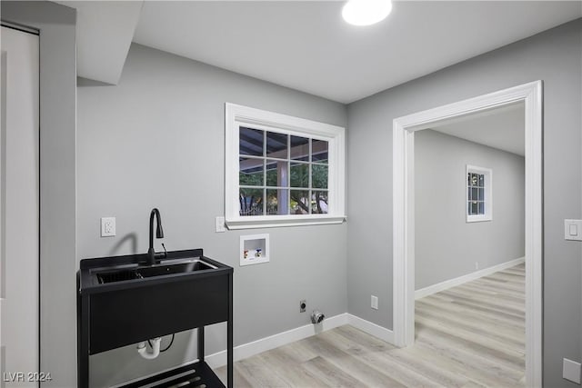 laundry room featuring baseboards, hookup for a washing machine, a sink, light wood-style floors, and laundry area