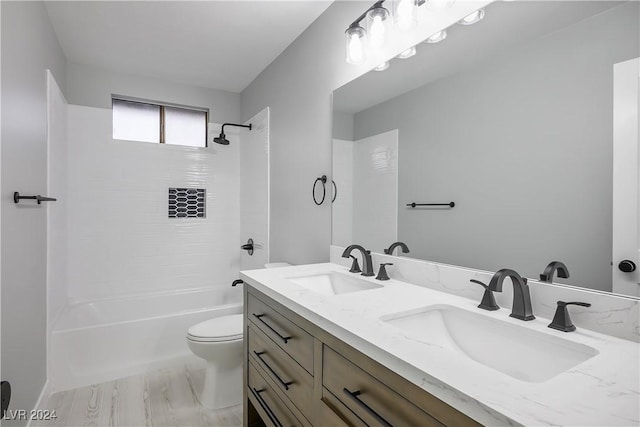 bathroom with toilet,  shower combination, double vanity, and a sink