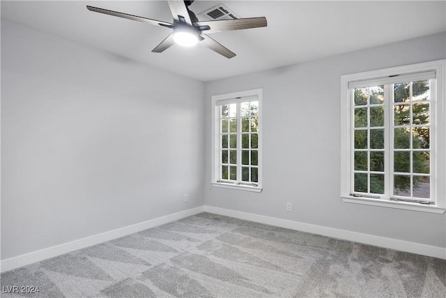 carpeted spare room with baseboards, visible vents, and a ceiling fan
