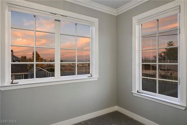 spare room with ornamental molding, baseboards, plenty of natural light, and dark carpet