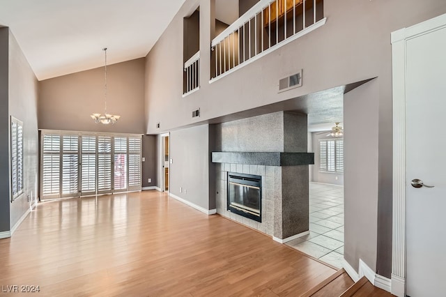 unfurnished living room with plenty of natural light, wood-type flooring, and ceiling fan with notable chandelier