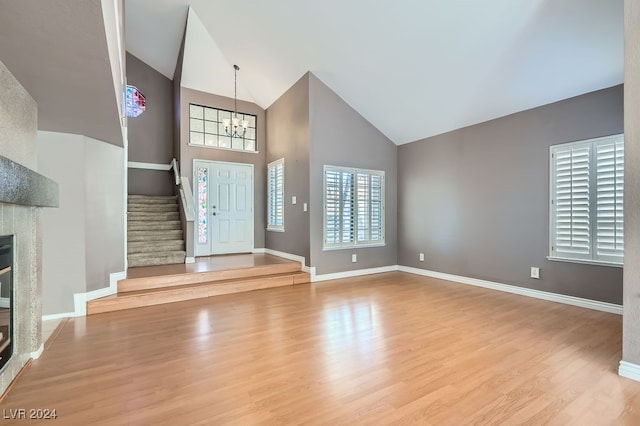 foyer entrance with light wood-type flooring, high vaulted ceiling, and an inviting chandelier