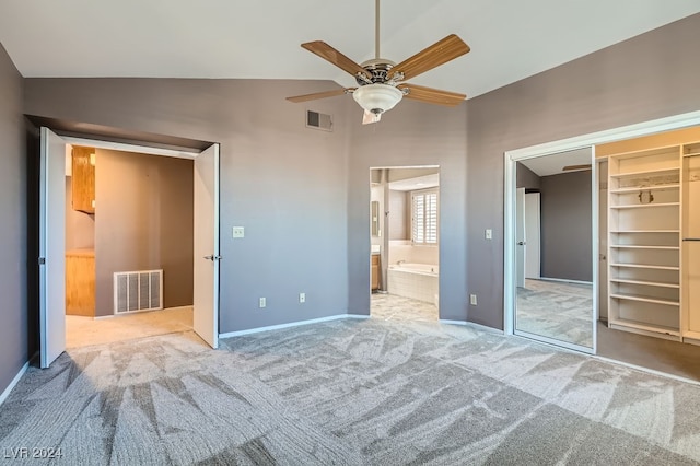 unfurnished bedroom featuring ensuite bathroom, vaulted ceiling, ceiling fan, light colored carpet, and a closet