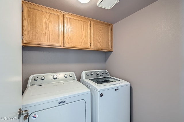 washroom with washing machine and clothes dryer and cabinets