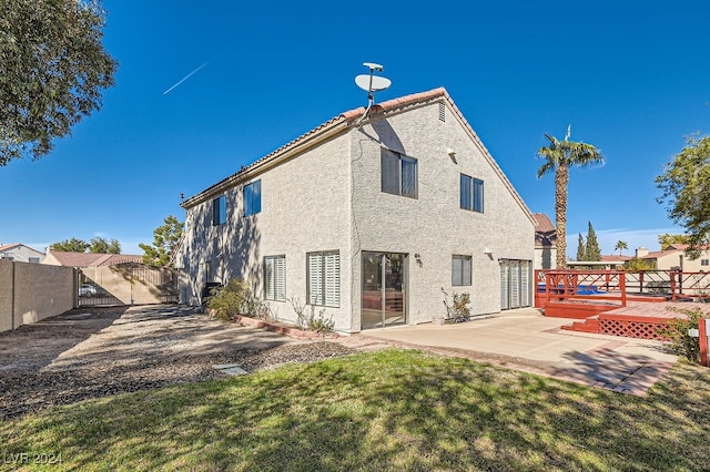 rear view of property featuring a yard, a deck, and a patio area