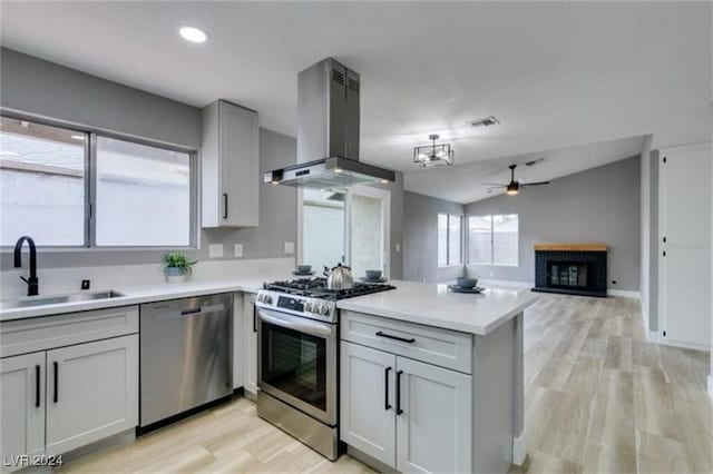 kitchen featuring appliances with stainless steel finishes, island range hood, light countertops, and a sink