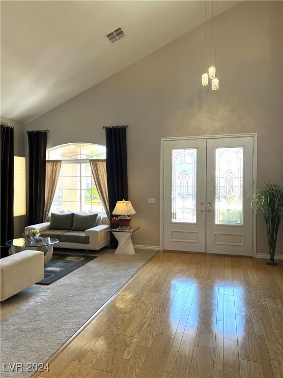 interior space with hardwood / wood-style floors, high vaulted ceiling, french doors, and an inviting chandelier