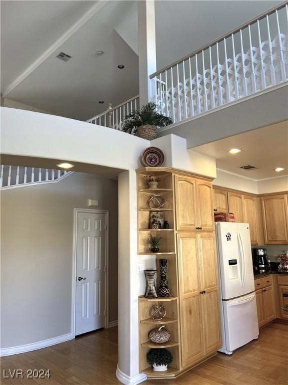 kitchen with a towering ceiling, wood-type flooring, and white refrigerator with ice dispenser