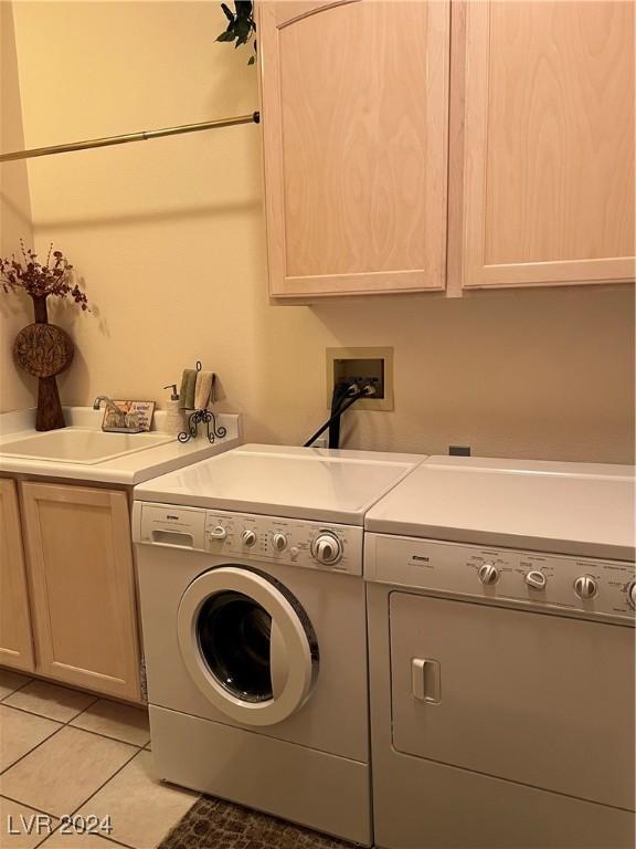 laundry room with light tile patterned flooring, cabinets, separate washer and dryer, and sink