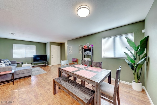 dining room with a textured ceiling and light hardwood / wood-style floors