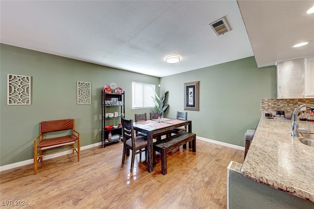 dining space featuring a textured ceiling, light hardwood / wood-style floors, and sink