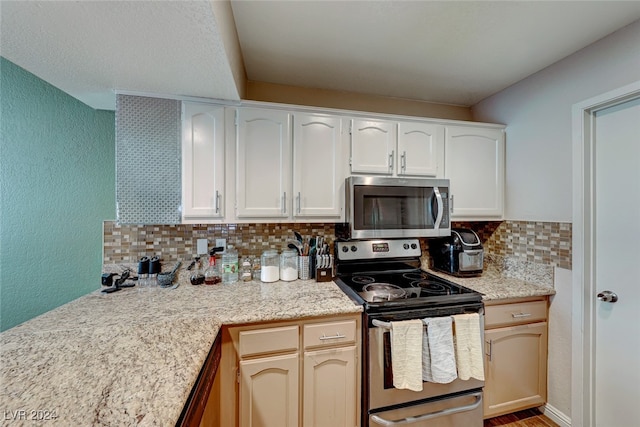 kitchen featuring backsplash, white cabinetry, stainless steel appliances, and light stone counters