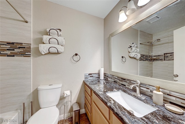 bathroom featuring a tile shower, backsplash, toilet, vanity, and hardwood / wood-style flooring