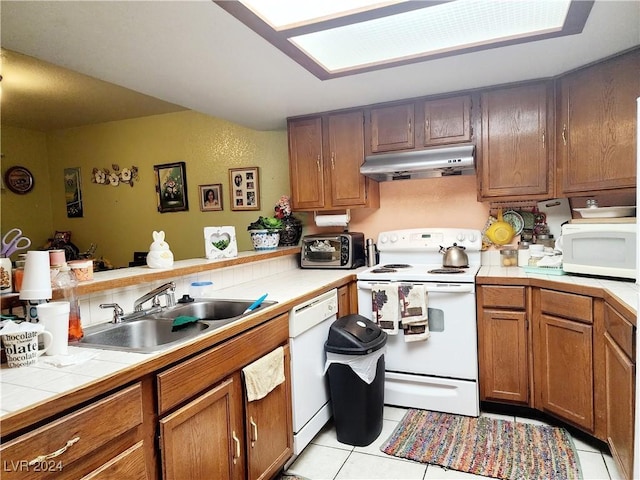 kitchen featuring tile countertops, light tile patterned flooring, white appliances, and sink