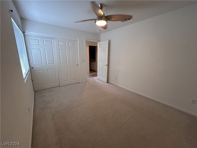 unfurnished bedroom with light carpet, a closet, and ceiling fan