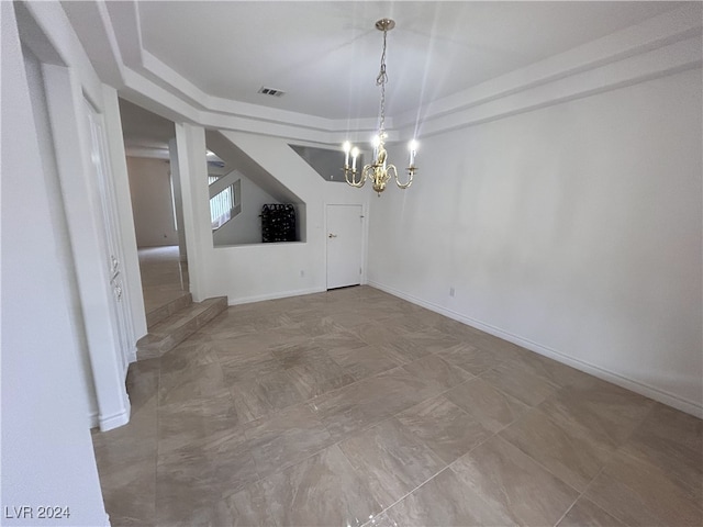 unfurnished dining area featuring a tray ceiling and an inviting chandelier