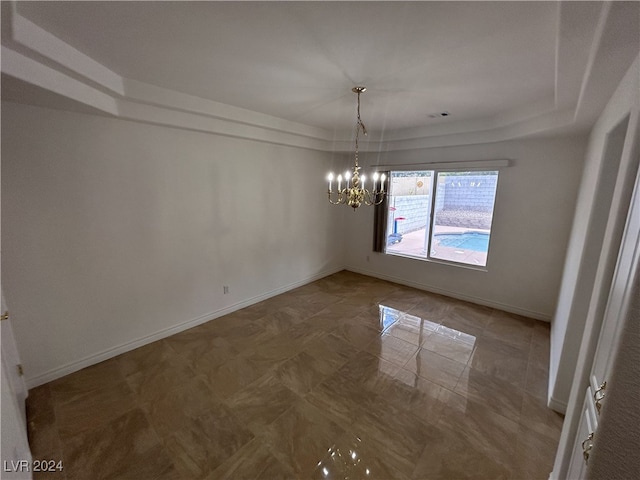 unfurnished dining area featuring a tray ceiling and a chandelier