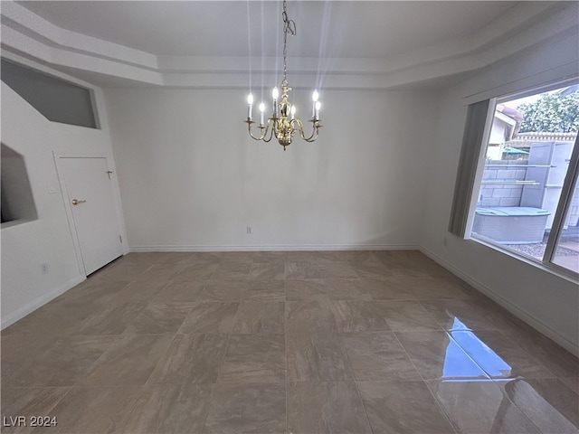 unfurnished dining area featuring a raised ceiling and a notable chandelier