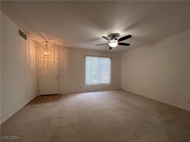 carpeted empty room with ceiling fan with notable chandelier