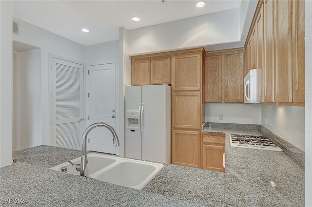 kitchen featuring light stone counters, sink, and white appliances