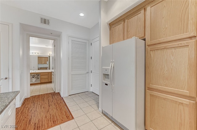 kitchen with light brown cabinets, light tile patterned floors, and white fridge with ice dispenser