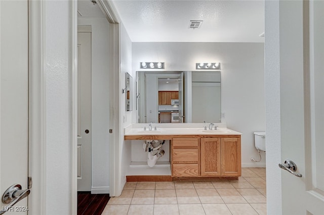 bathroom with toilet, vanity, and tile patterned floors