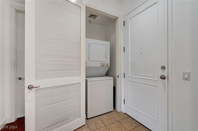 clothes washing area with light tile patterned floors and stacked washer and clothes dryer