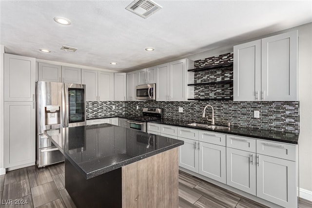 kitchen featuring a center island, backsplash, sink, dark stone countertops, and appliances with stainless steel finishes