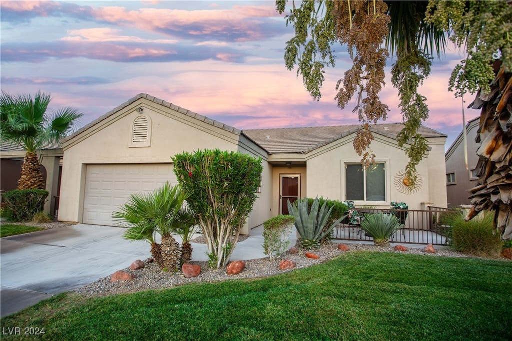 ranch-style house featuring a garage and a yard