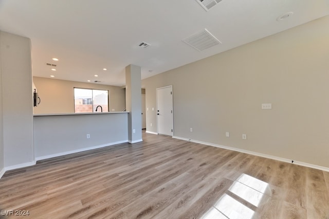 unfurnished living room with light wood-type flooring and sink