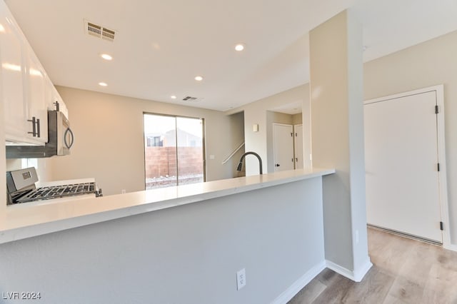 kitchen with appliances with stainless steel finishes, white cabinetry, light hardwood / wood-style flooring, and sink