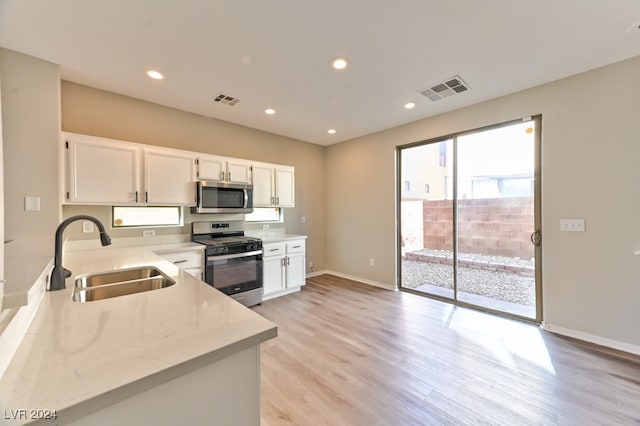 kitchen featuring light stone countertops, appliances with stainless steel finishes, light wood-type flooring, sink, and white cabinets