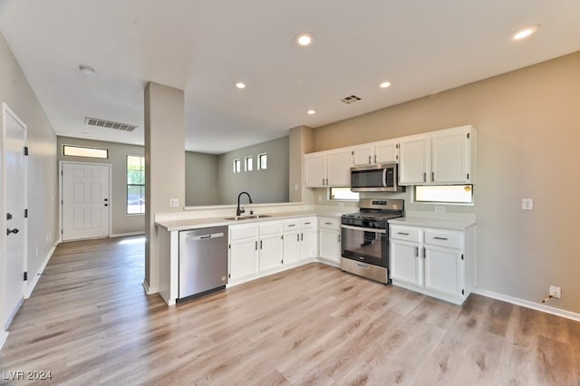 kitchen with white cabinetry, sink, stainless steel appliances, and light hardwood / wood-style flooring