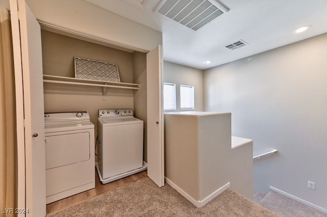 washroom with washer and clothes dryer and light wood-type flooring