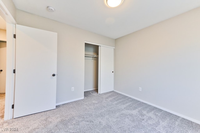 unfurnished bedroom with light colored carpet and a closet