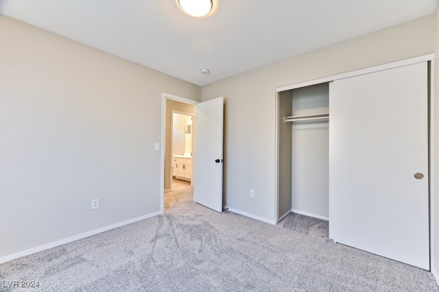 unfurnished bedroom with light colored carpet and a closet